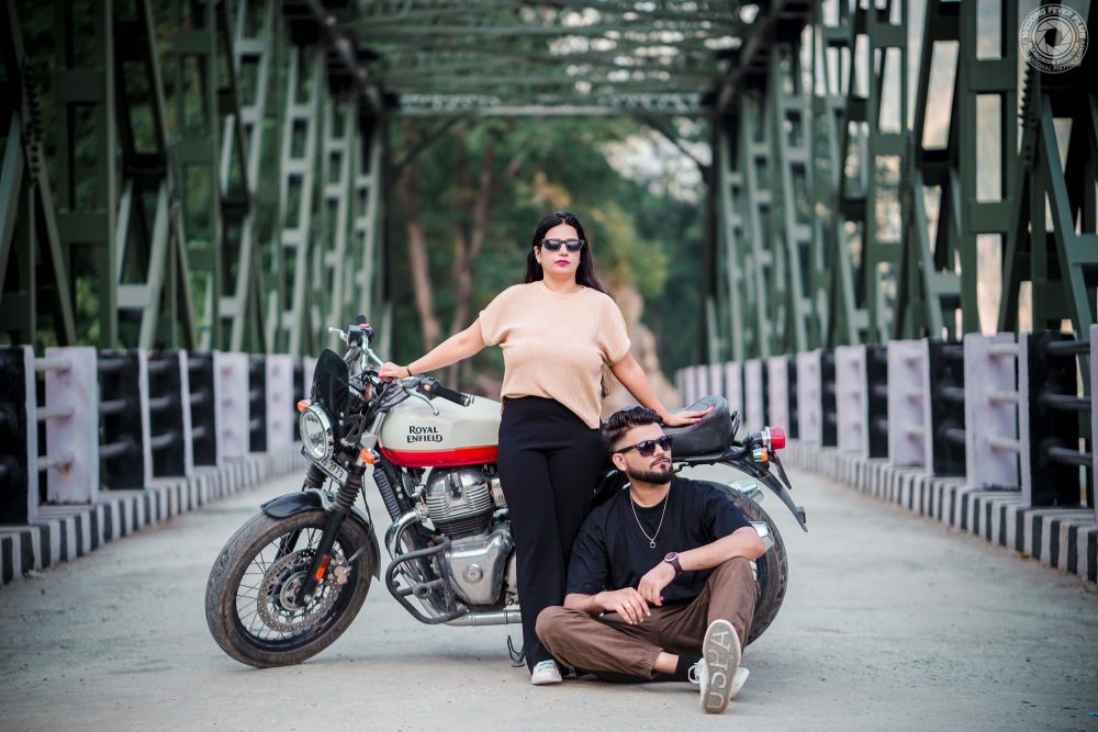 Couple posing with bike on iconic bridge in Rishikesh pre-wedding shoot.